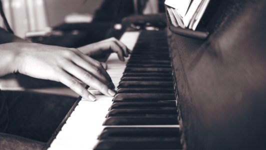 person playing upright piano in sephia photography photo