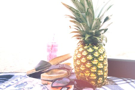 minimalist photography of pineapple near sandals and sunglasses photo
