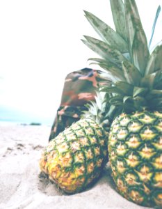 two pineapples on gray sand photo
