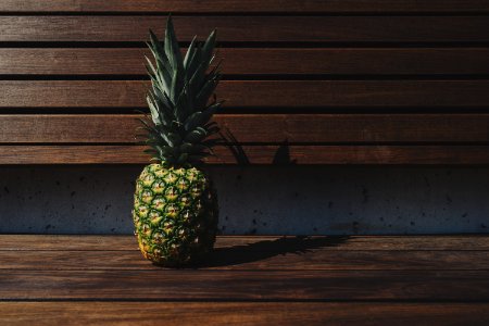 green and yellow pineapple placed on brown wooden pallet bench photo