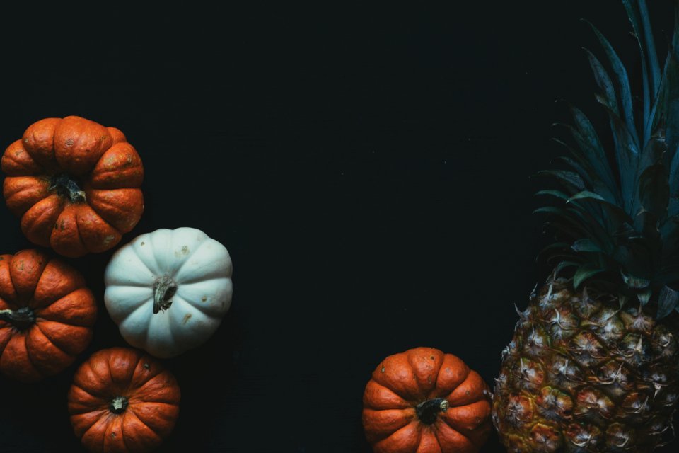 four orange and white pumpkin squashes and one pineapple