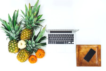 pineapple fruits near MacBook on white surface photo