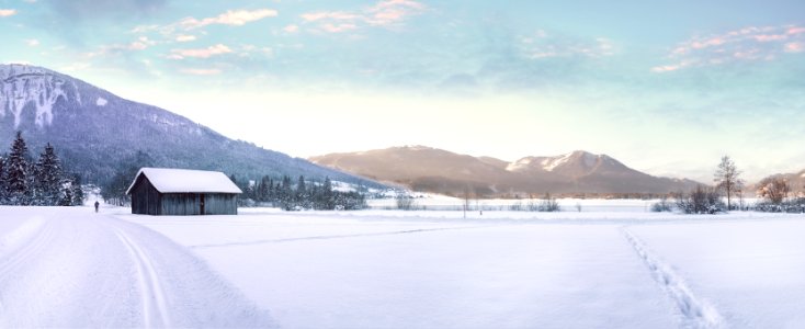 An old cottage in a snow covered field near winter alps.