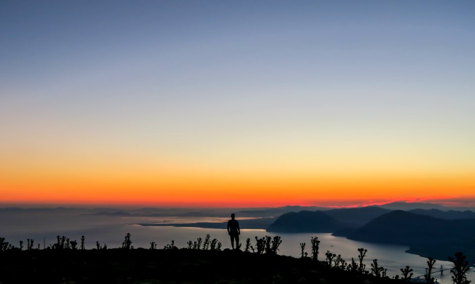 silhouette photo of man standing on mountain photo