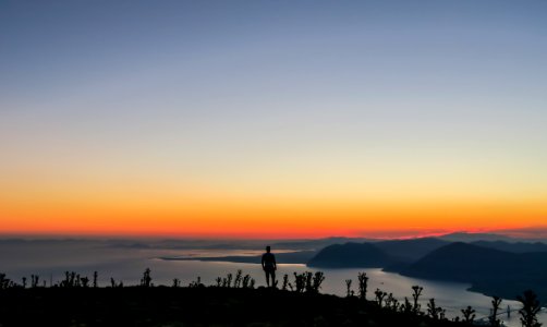 silhouette photo of man standing on mountain photo