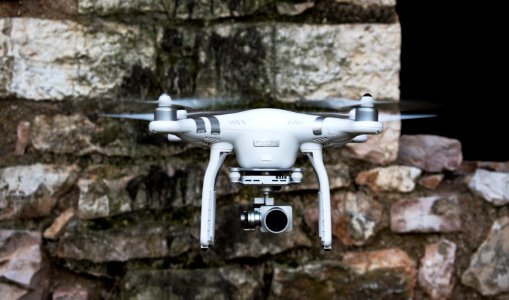 white and silver DJI quadcopter near brown concrete wall during daytime