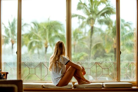 woman sitting on white cushion near glass window photo