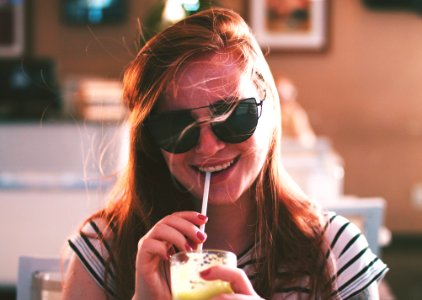 woman sipping drink while smiling photo