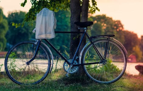 white cloth hanged on bike's handlebar leaned on tree photo