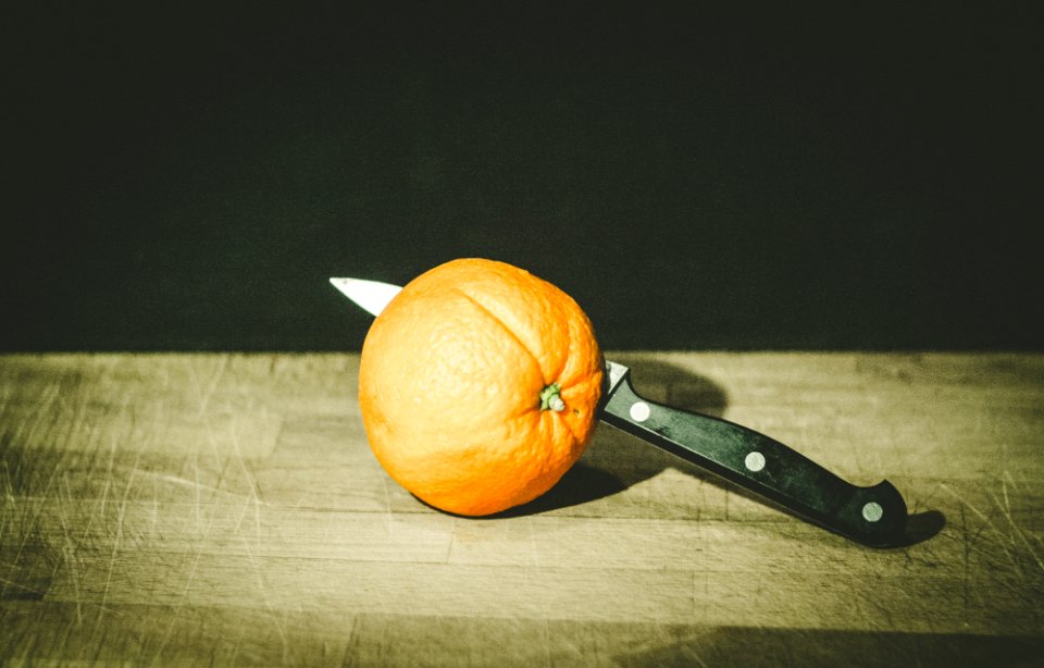 orange fruit and gray and black knife on brown wooden board low-light photography