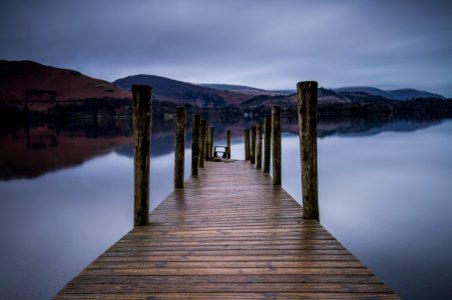 brown wooden dock on body of water overlooking mountains photo