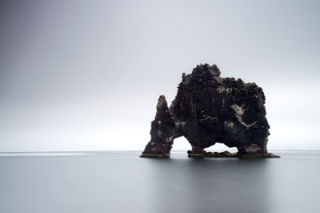 black rock formation on body of water photo
