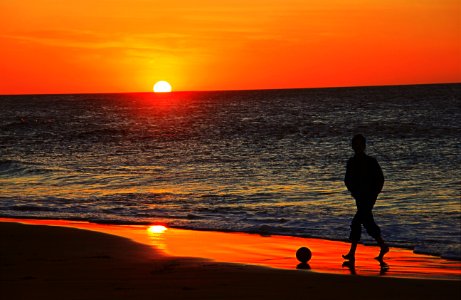 silhouette of man walking on beach during sunset photo
