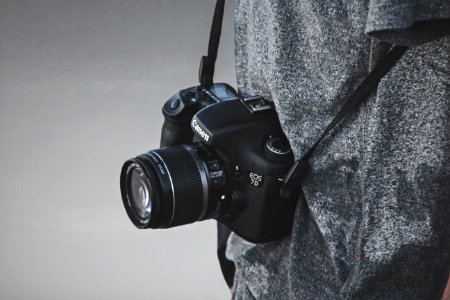 black nikon dslr camera on gray textile photo