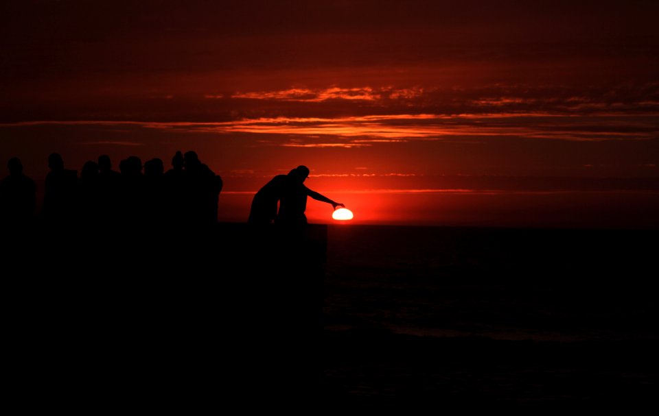 silhouette of people standing on beach during sunset