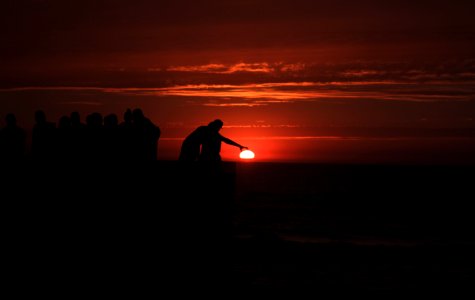 silhouette of people standing on beach during sunset photo