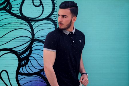 man in black polo shirt standing beside wall