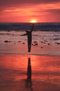 woman in black dress standing on beach during sunset photo