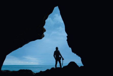 silhouette of person standing on rock photo