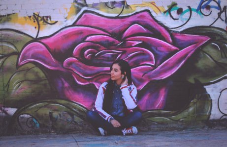 woman sitting beside purple flower wall painting