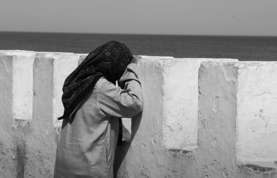 person in gray hoodie standing on gray concrete wall during daytime photo