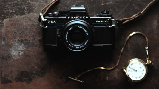 black Praktica camera and gold-colored pocket watch photo