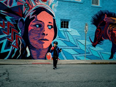 boy standing near vandalism art during daytime photo