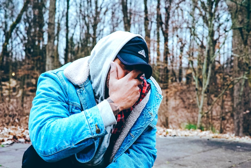 man in blue denim jacket covering his mouth with hand photo