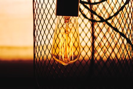 silhouette photo of light bulb near chain-link fence photo