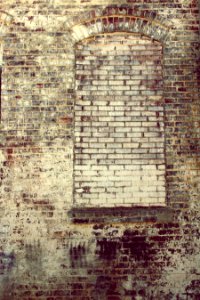 A brick building with bricks covering the opening where a window once was. photo