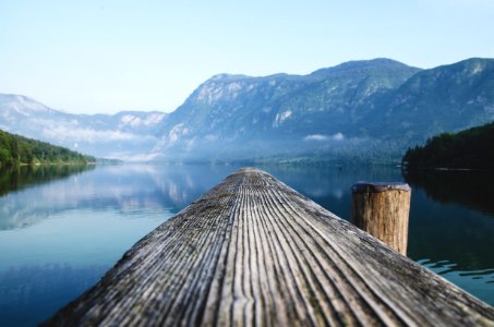 gray wood beam near body of water surrounded by mountain ranges during daytime photo