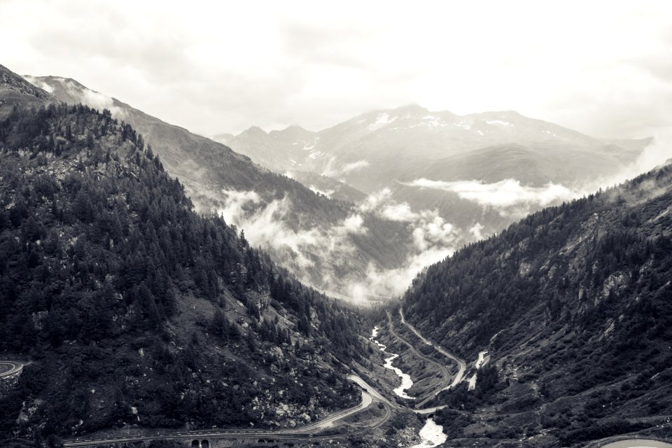 grayscale photography of river and road at the mountain during day