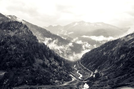 grayscale photography of river and road at the mountain during day