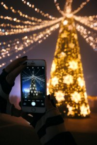 A person taking a picture of their Christmas tree with their smartphone. photo