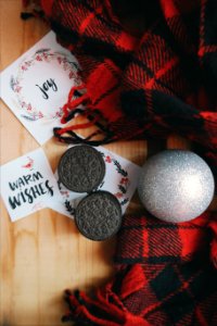 Oreo cookies around Christmas paper notes, an ornament and red plaid fabric.