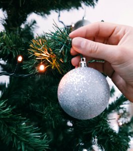 A person hanging a silver ornament to an XMAS tree. photo