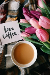 A "love coffee," note next to a creamy cup of coffee and flowers.