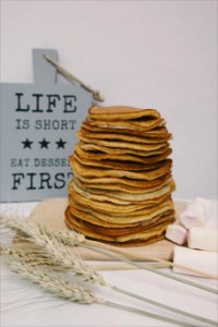 A pile of pancakes in front of a blue sign that says "Life is short - Eat pancakes first." photo
