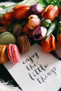 A piece of paper next to colorful snacks that reads "Enjoy the little things." photo