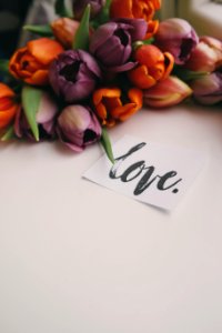 Bouquet of tulips, next to a slip of paper that reads "love" in cursive writing photo
