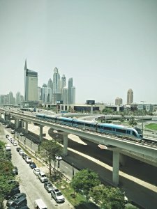 blue train near high-rise buildings under gray sky at daytime photo