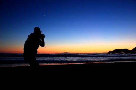 silhouette of person standing near seashore photo