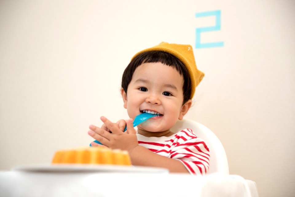 baby sitting on white chair while smiling at the camera
