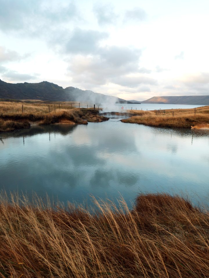 lake near mountain under cloudy sky at daytime