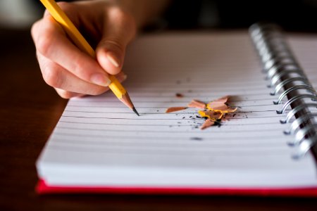 person holding pencil writing on notebook photo
