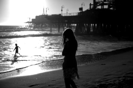 grayscale photography of woman standing in beach photo