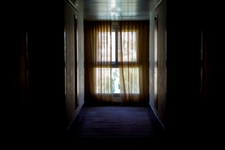 hallway leading to window covered by brown window curtain