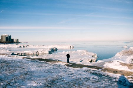 man stands between snowfield near body of water photo