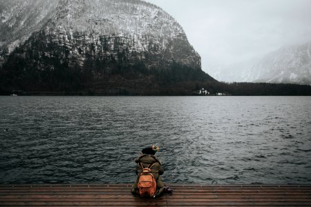 person sitting on wooden dock in front of body of water photo