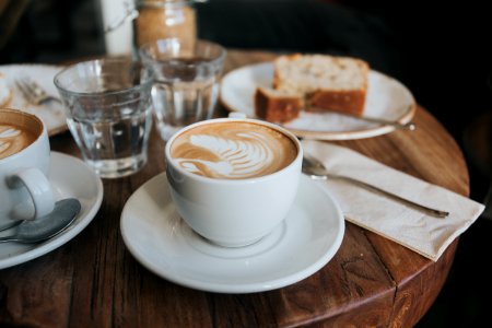 white ceramic mug on white ceramic saucer on brown wooden table photo